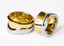 Zwei gold und silberne Hochzeitsringe mit Diamantbesatz liegen übereinander