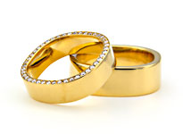 Zwei goldene Hochzeitsringe mit Diamantbesatz und eckiger Form liegen übereinander