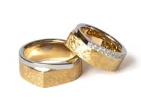 Zwei gold-silberne Hochzeitsringe mit eckiger Form liegen übereinander