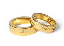 Zwei Goldene Hochzeitsringe mit Diamantbesatz liegen übereinander