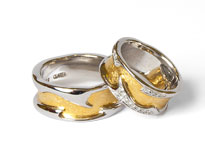 Zwei gold-silberne Hochzeitsringe mit Muster liegen übereinander