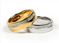 Ein goldener und silberner Hochzeitsring mit Diamantbesatz liegen übereinander