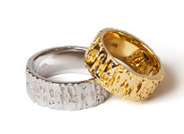 Ein goldener und silberner Hochzeitsring mit Struktur liegen übereinander